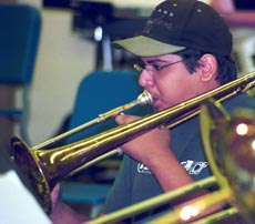 Paul Deltoro, an assistant in the Pep Band class, focuses on reading his music and leading the trombone section during a Saturday morning rehearsal. The band has been revived this season to play at home games.</fo