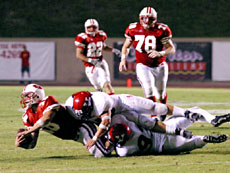 Quarterback Justin Heimiller is taken down by two Vaqueros players.