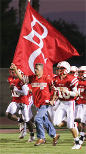 Former Bakersfield College student and long time fan of the Renegade football team Peter Reyes leads the players onto the field at the start of a game against Pasadena City College on Oct. 3.