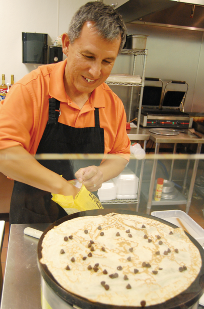 Andres Barragan, owner of Cafe Crepes, sprinkles chocolate chips over a crepe on Nov. 25.