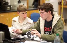 Joshua Wittenberg (left) and his brother Grant Wittenberg (right) are busy programing their robot with their computer Feb. 17