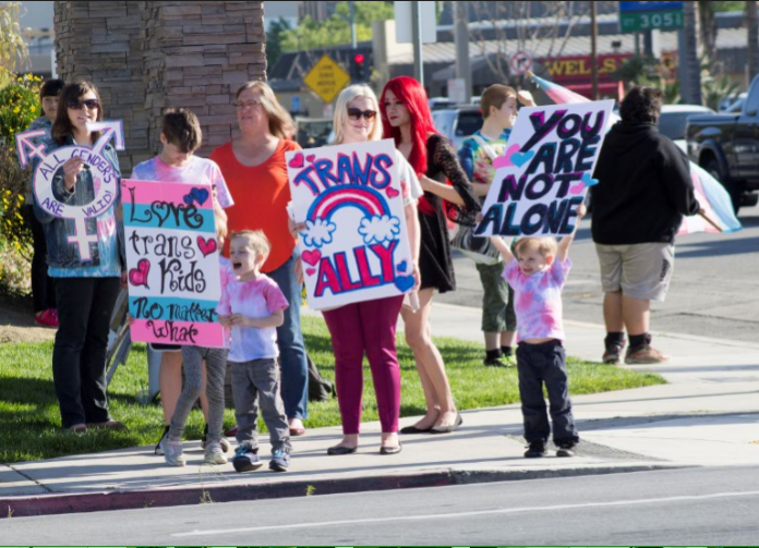 The King family stands at the intersection of 24th and L streets holding their signs in support of the trans community.