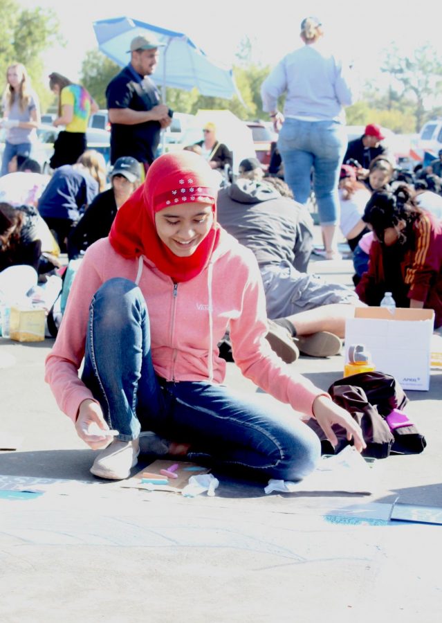 Stockdale High School student Eesha Sohail smiles as she works on her chalk art piece at the local Via Arte event.