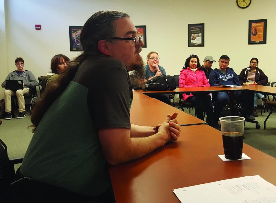 The audience of the Gadfly Café looks at Reggie Williams as he speaks.