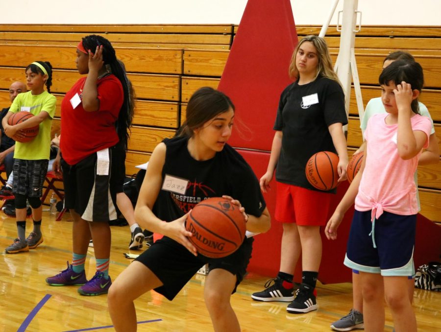 BC student and basketball player Jasmyn Rodriguez showing her group how to crouch and turn without losing balance, as a part of the BC Basketball Academy. 