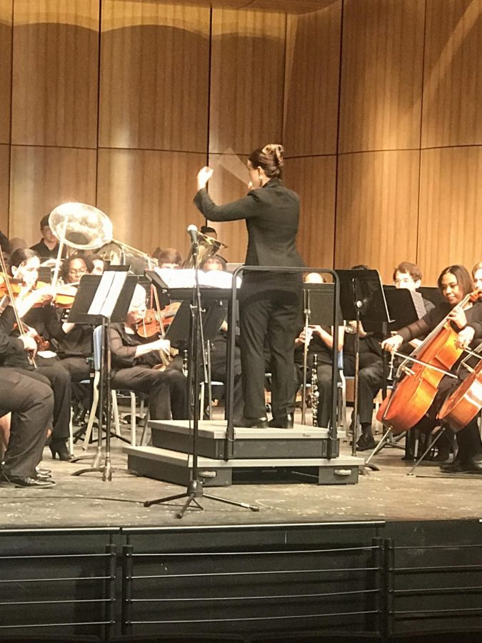 Music professor Kathryn Kuby conducting Concert Band and Orchestra while performing “On Top of the World” by Brian Balmages.  