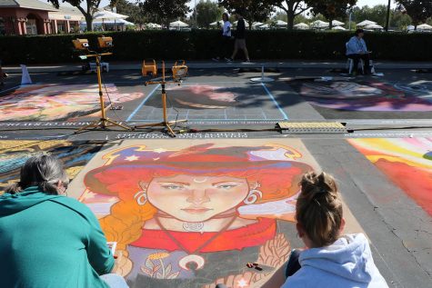 Jennifer Williams (left) and Darla Kendrick (right) drawing an herb witch inspired piece of chalk art at the Via Arté event on Oct. 20. 