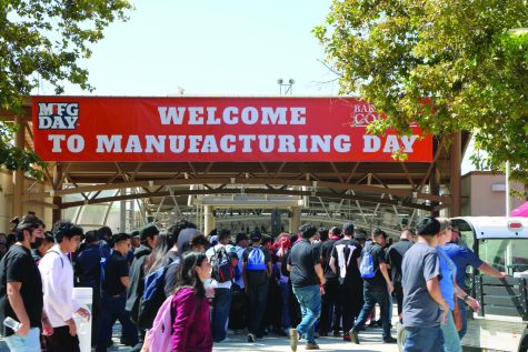 Welcome to Manufacturing Day sign (white lettering on red background) with students walking around in front of it