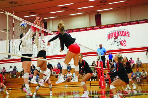 volleyball players jump to hit ball over net during game