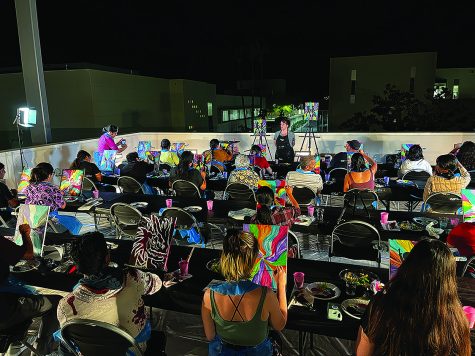 Rows of chairs with people sitting in them watching an instructor in an outdoor space at night