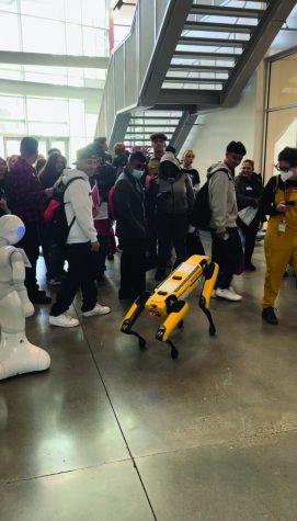a yellow robot dog in front of a group of students