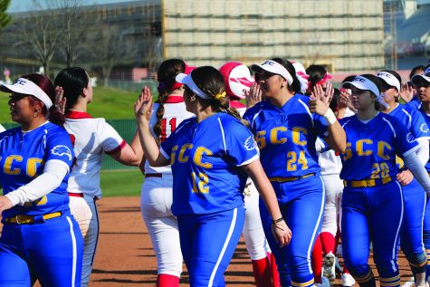 women on both softball teams give each other high fives 