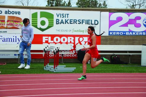 Woman running wearing read uniform and green shoes.