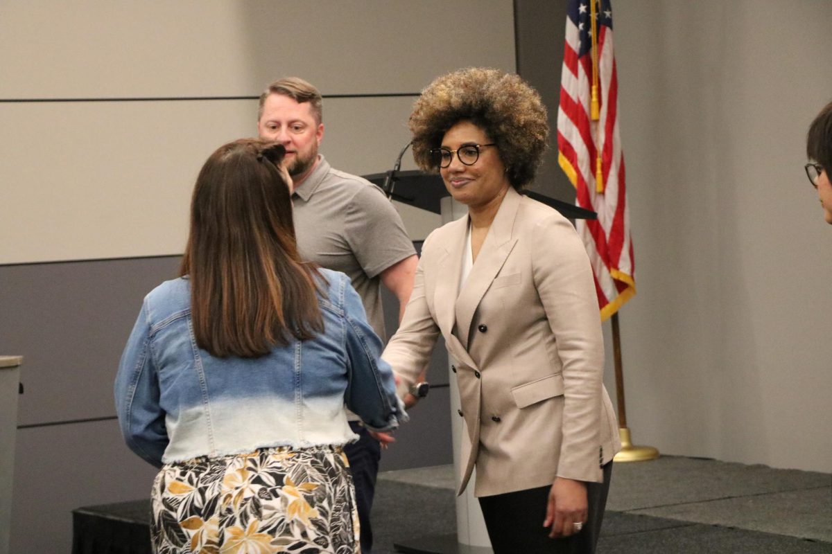 A woman shaking hands with an audience member.